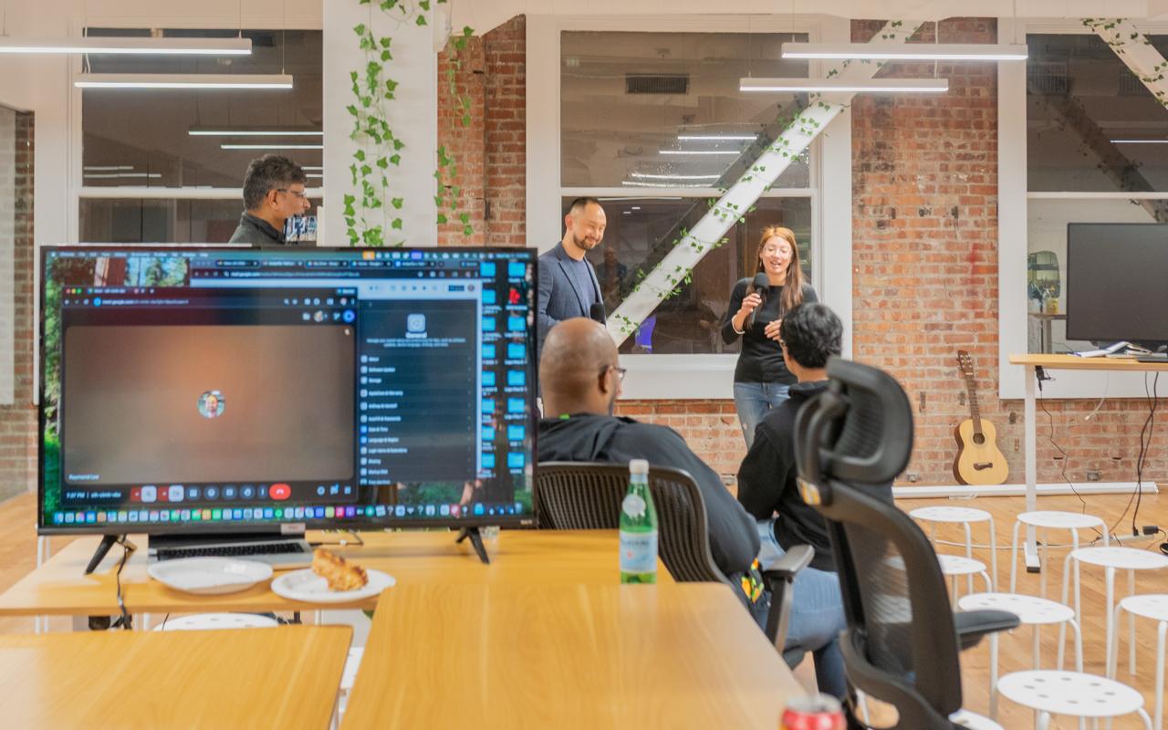 Community event in the loft — presenting with exposed brick, plants, and guitar visible